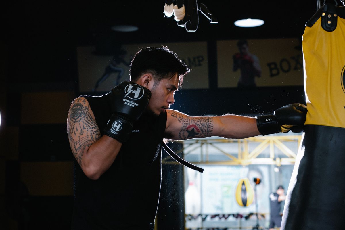 Boxer striking a heavy bag during combat training in a gym