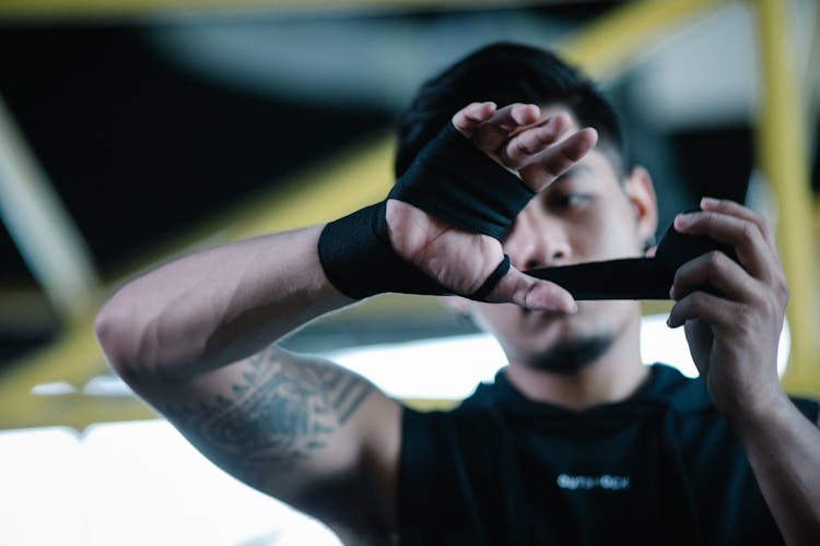 Man Wrapping Hands With Black Boxing Wraps