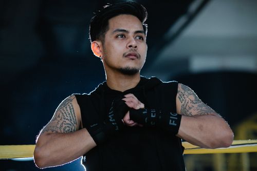 Free Asian boxer with tattoos connecting hands and looking away during workout on blurred background Stock Photo