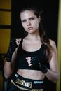 Young female boxer with long hair and bandaged hands standing in fighting stance and looking at camera