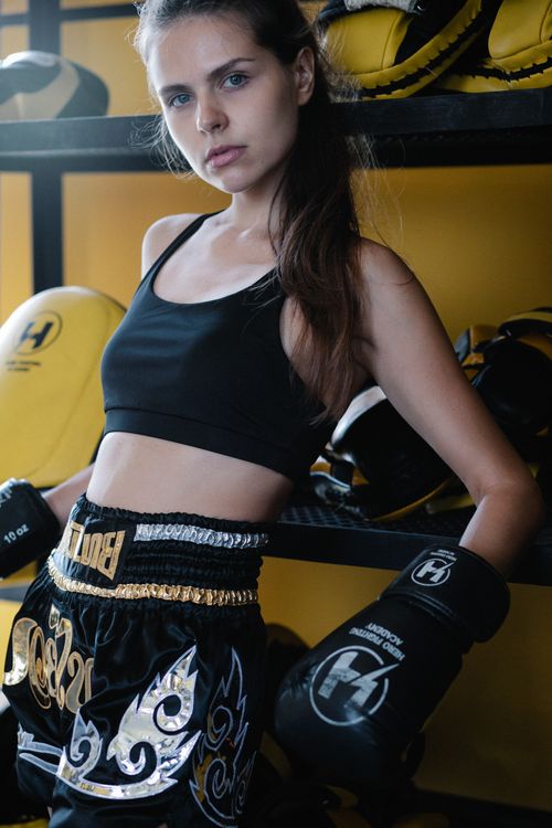 Free Long haired female athlete in boxing gloves leaning on shelves and looking at camera Stock Photo