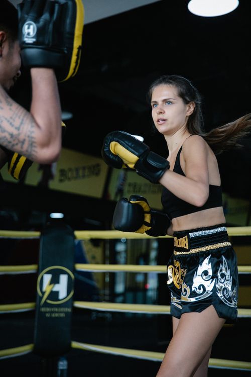 Free Focused woman practicing boxing in a gym with a trainer, showcasing intense athleticism and dedication. Stock Photo