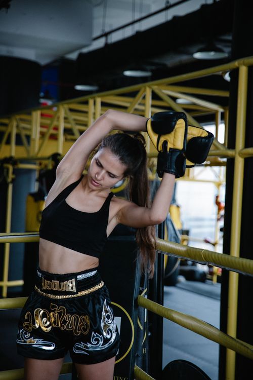 Free Woman in sportswear warming up with boxing gloves in a gym setting. Stock Photo