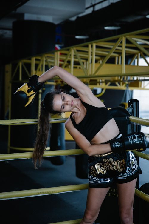 Free Female boxer wearing boxing gloves stretching in a boxing ring. Stock Photo