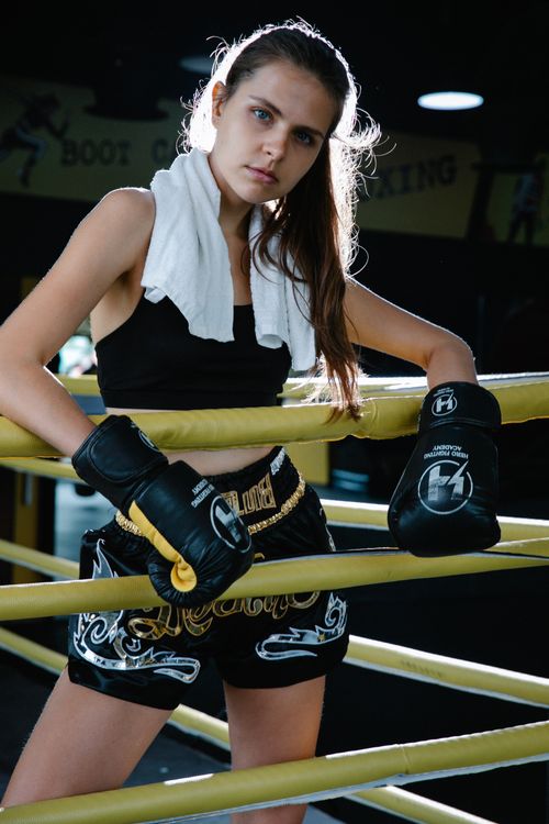 Free Confident female boxer resting between ropes in gym with gloves and towel. Stock Photo