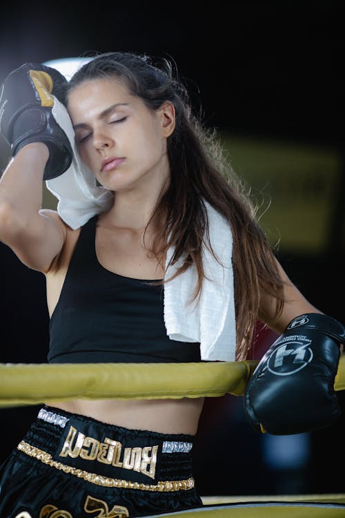 Free A Woman Wearing Boxing Gloves Wiping her Face with a Towel Stock Photo