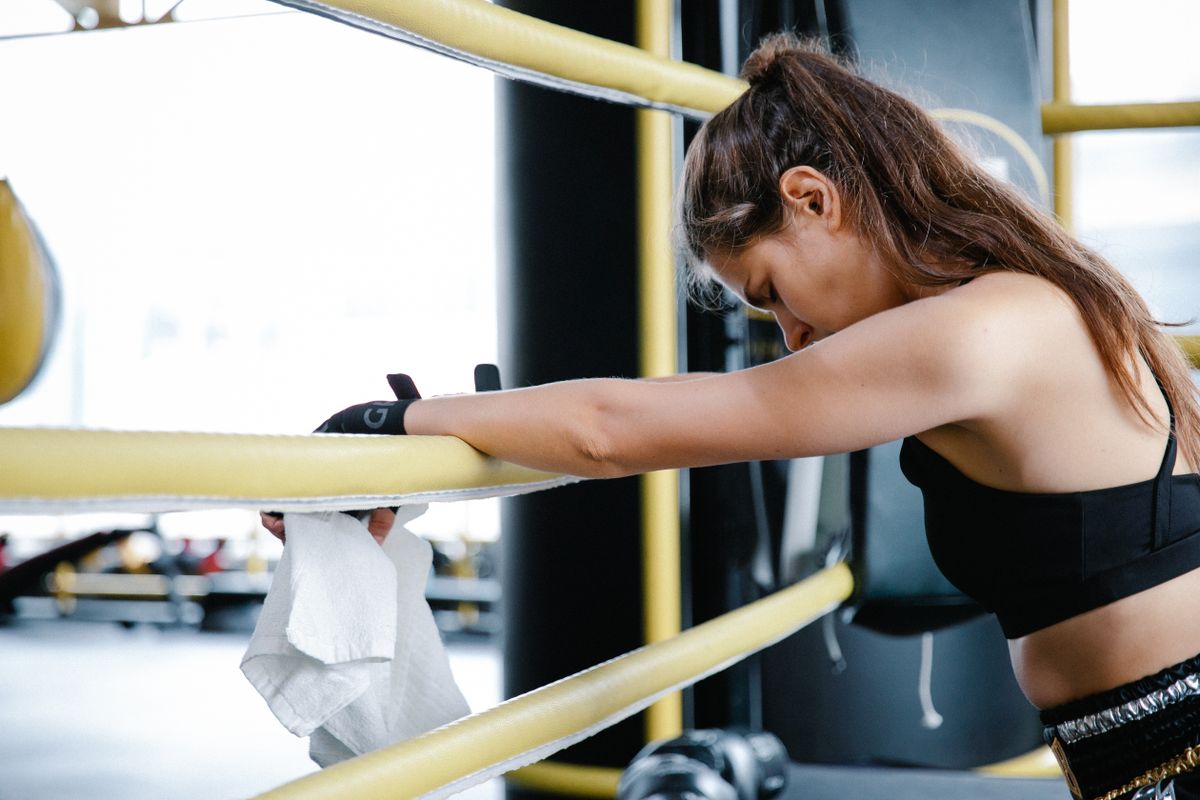 Exhausted person resting on gym ring ropes after a hard training session