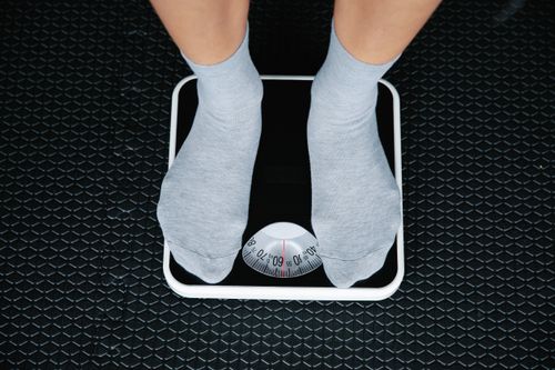 Free Top view of feet in socks standing on a bathroom scale, indicating weight measurement. Stock Photo