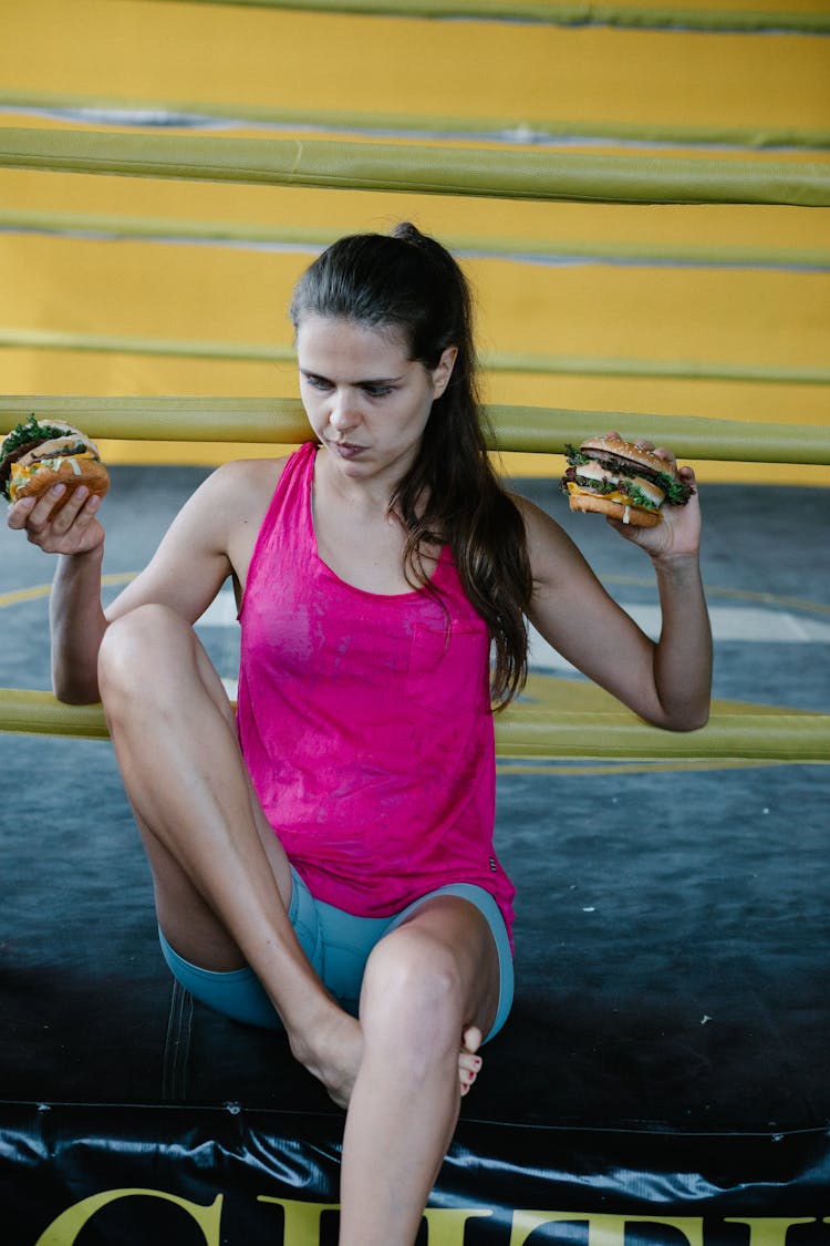 Woman Sitting At Boxing Ring With Two Burgers