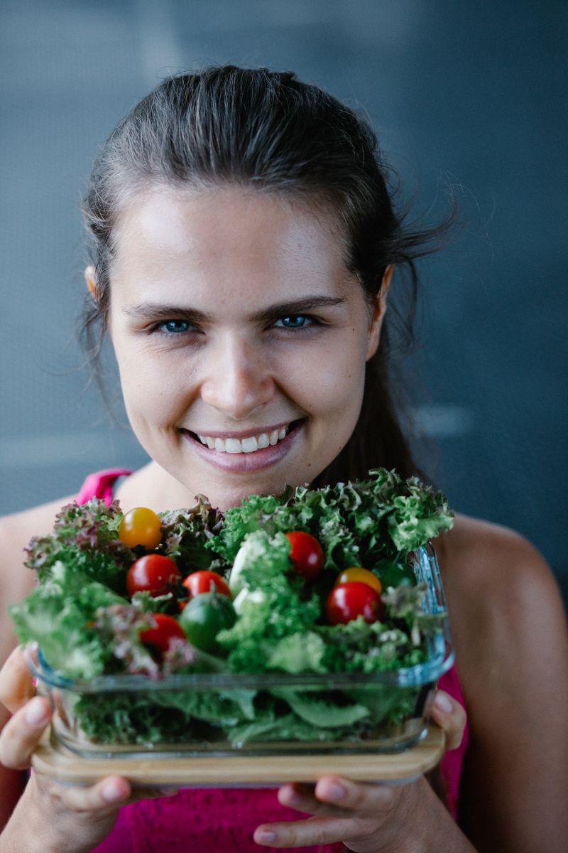 Nutrition client smiling while holding a container of fresh salad