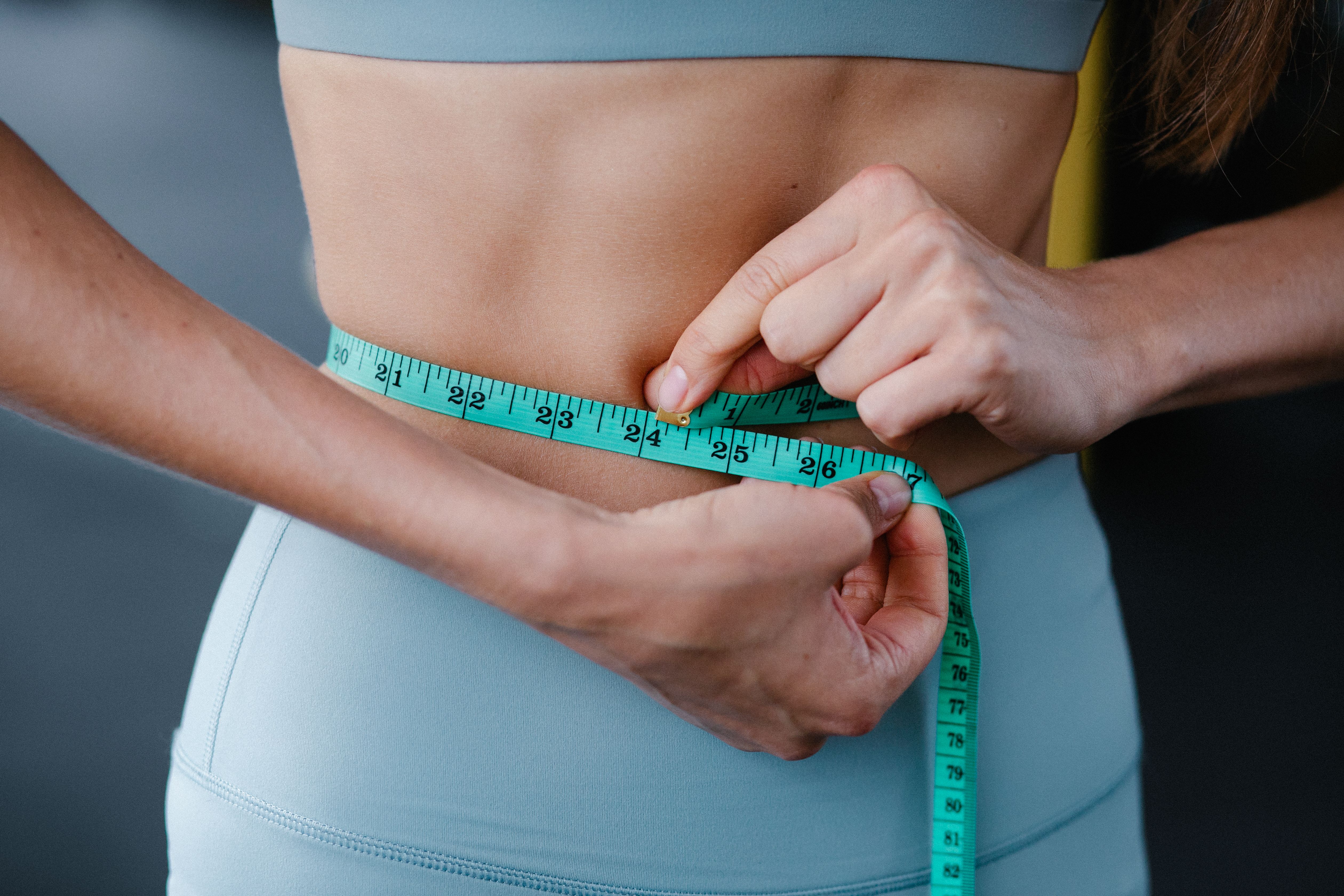 Person measuring waist showing weight loss results