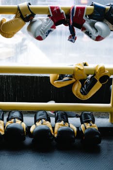 Various colored boxing gloves hanging on gym railings, showcasing sports equipment.