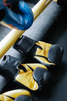 Yellow and black boxing gloves on a gym mat, emphasizing sports training equipment.