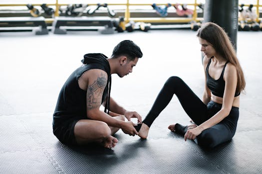 A personal trainer helps a woman with an ankle bandage in a gym setting.