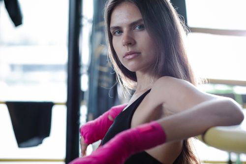 Free Portrait of a female boxer with pink hand wraps, exuding confidence while training indoors. Stock Photo