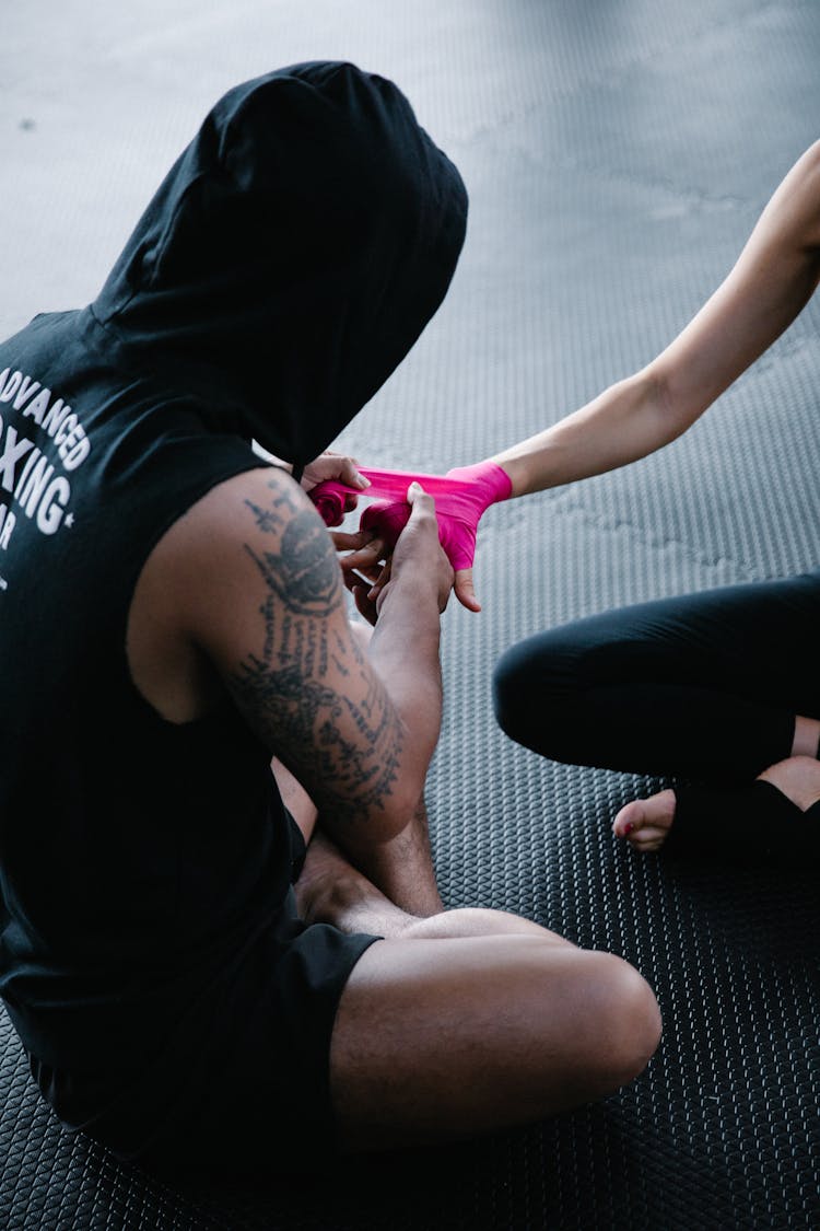 Man In A Hood Putting A Pink Protective Bandage On Womans Hand