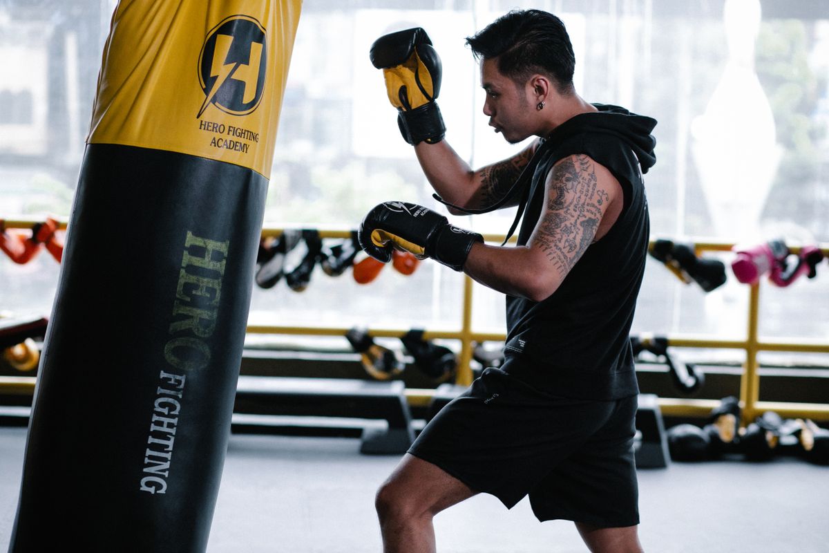 Boxer training with a heavy punching bag in an indoor gym