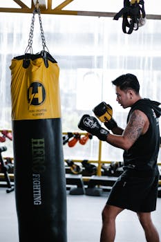 Athletic man engages in boxing training with a vibrant punching bag in an indoor gym setting.