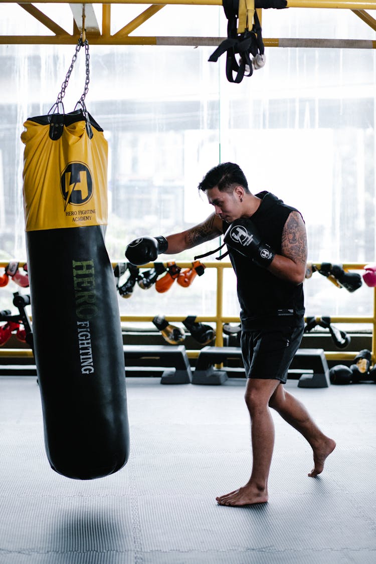 A Man Wearing A Boxing Gloves While Hitting A Punching Bag