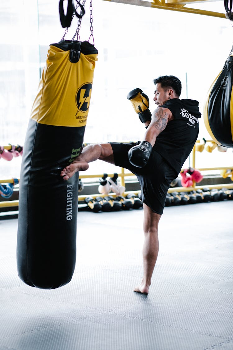 A Man Kicking A Punching Bag