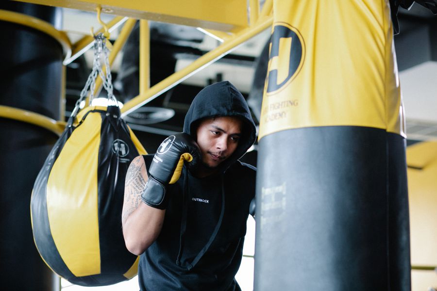 Hombre con hoodie golpeando saco de boxeo