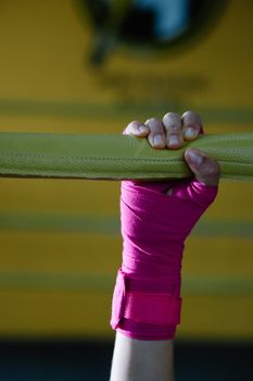 A hand using gym equipment with pink wraps, emphasizing sport and protection.