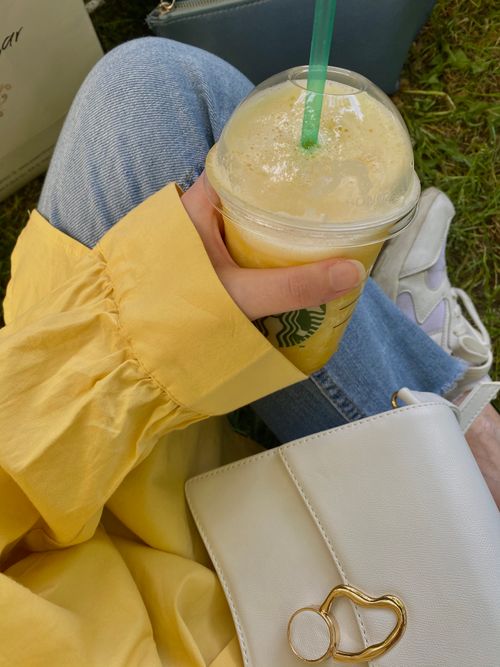 Free Woman holding a plastic cup with a refreshing drink, enjoying outdoors in casual clothing. Stock Photo