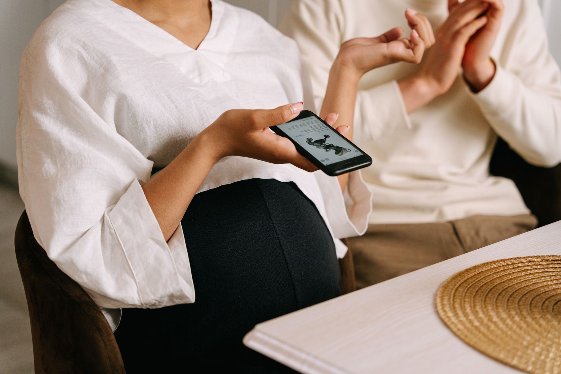 Pregnant woman holding smartphone indoors, capturing intimate family moments with technology.