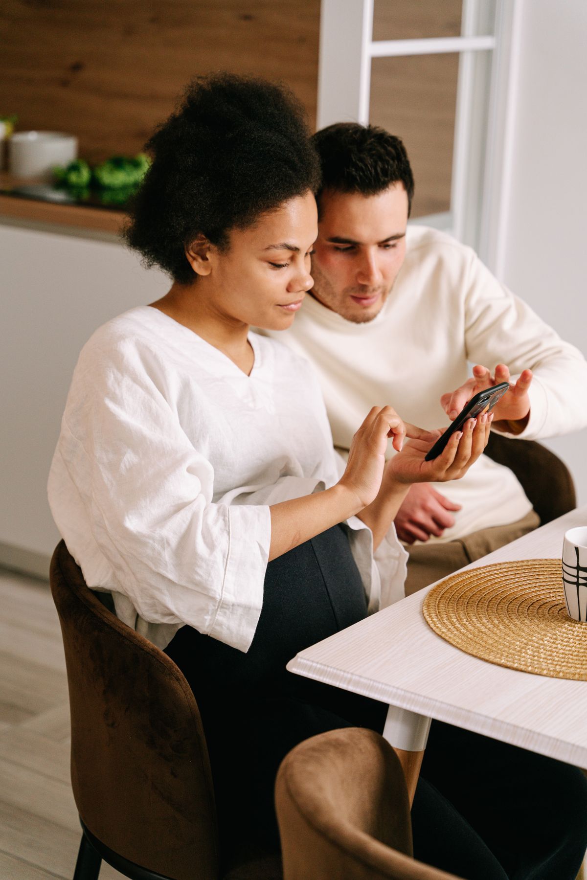 Pregnant couple using a smartphone while shopping online at home