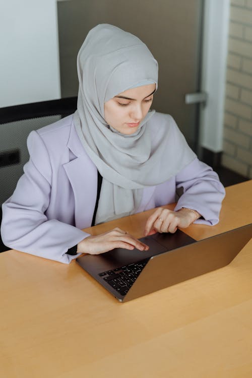 A Woman Wearing Hijab while Looking on Her Laptop