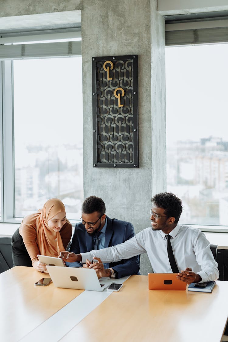 A Group Of People Having Conversation Inside The Office While Looking At The Tablet