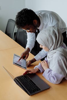 Two colleagues collaborating with digital devices in a modern office setting.