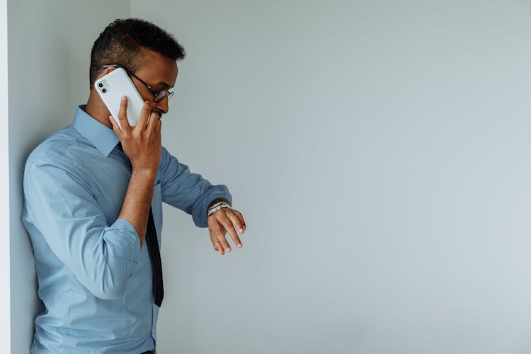 A Man Talking On The Phone While Looking At His Watch