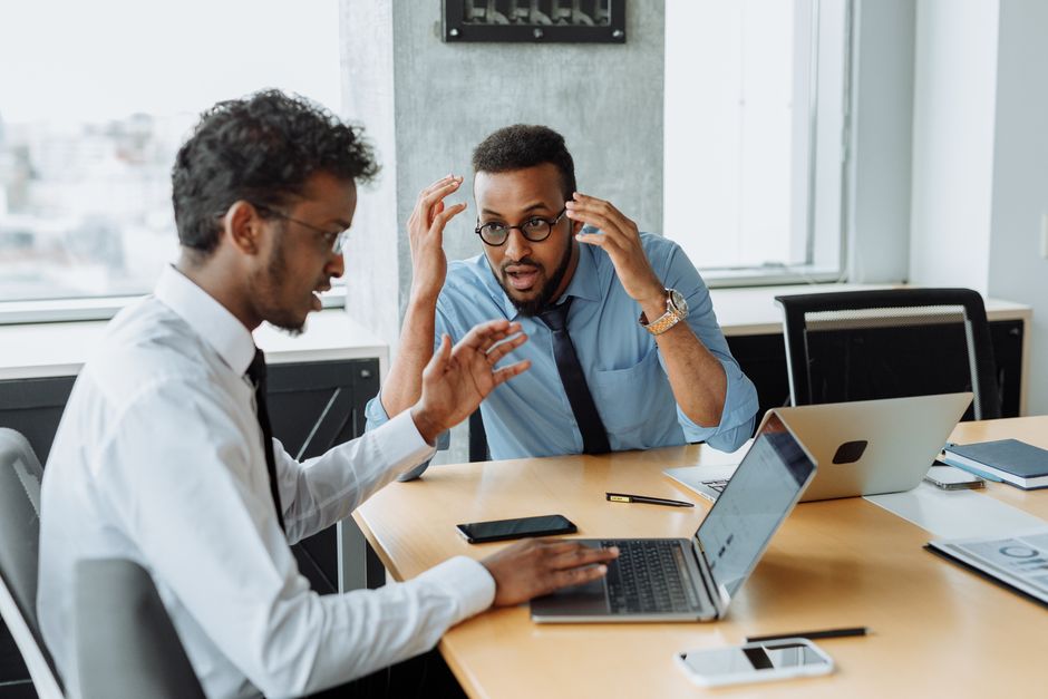 Two colleagues discussing a project with laptops during a brainstorming session in an office setting. Two colleagues discussing a project with laptops during a brainstorming session in an office setting.