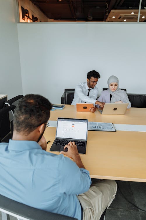 Man in White Long Sleeve Shirt Sitting beside Woman in Gray Hijab