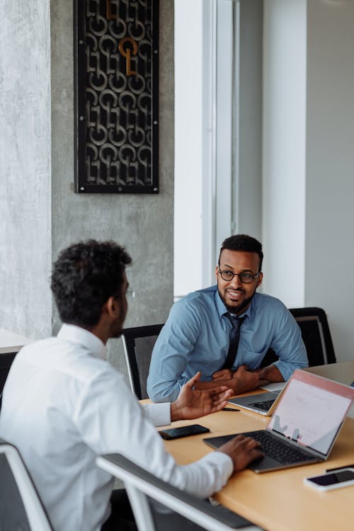 Free Two Men Sitting at Table and Talking in the Office Stock Photo