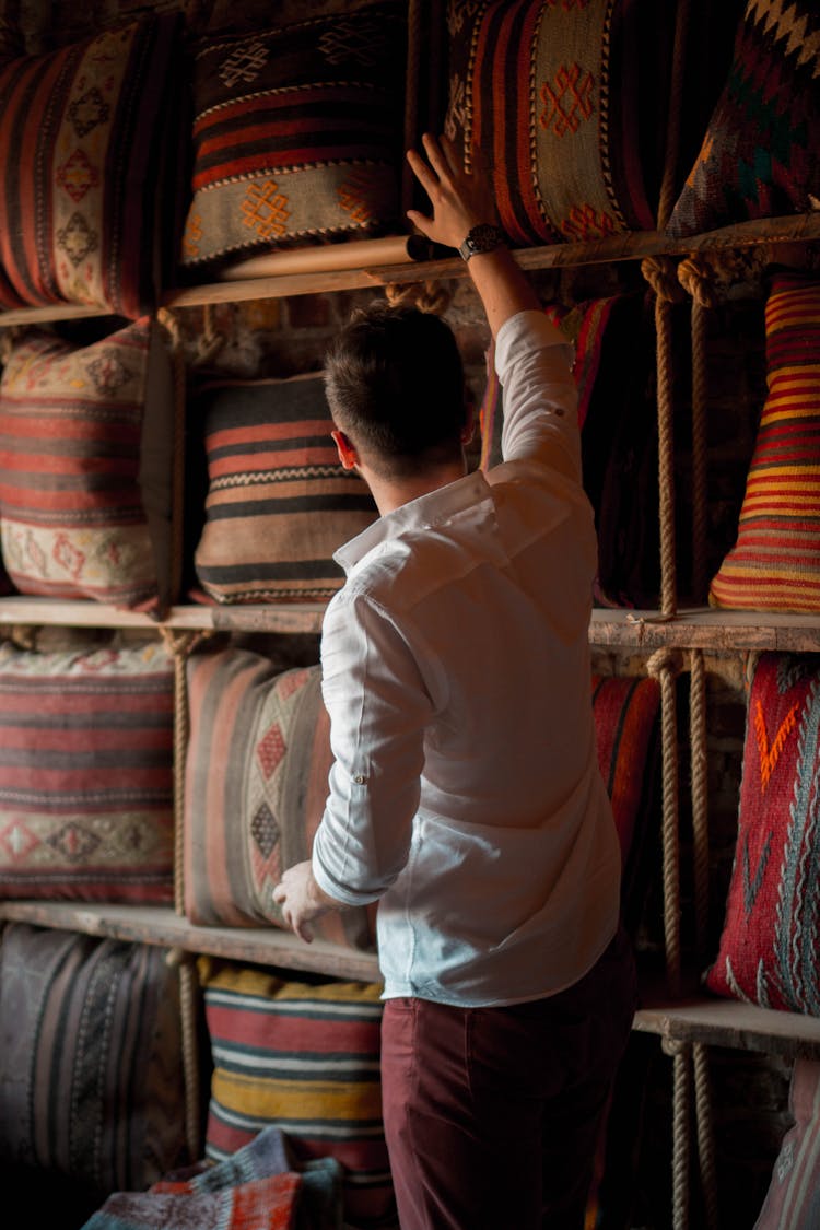 Man In White Shirt Showing Pillows On Shelves