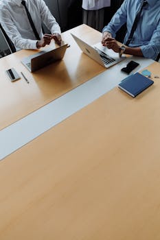 Colleagues collaborating over laptops and notebooks in a modern office.