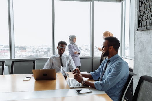 A diverse group of professionals collaborating in a modern office setting with laptops and smartphones.