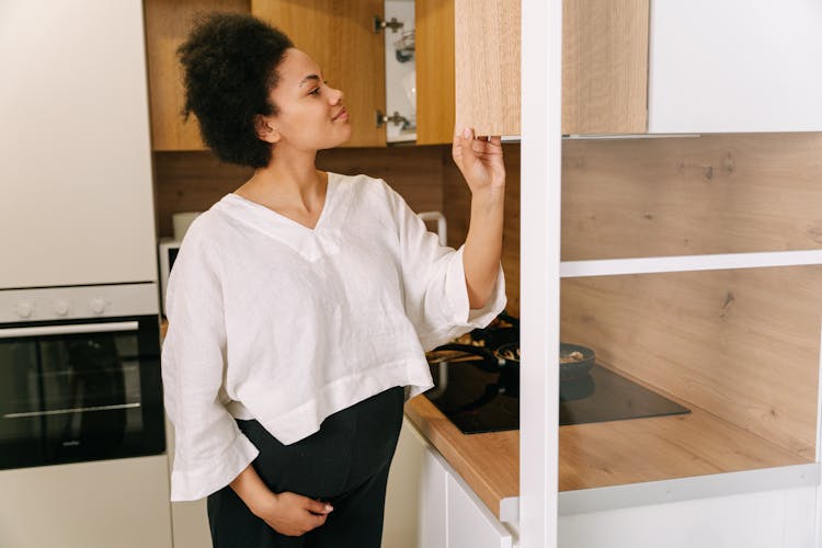 A Woman Looking At The Kitchen Cabinets