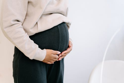 Pregnant Woman in Black Pants Holding Hands on Belly