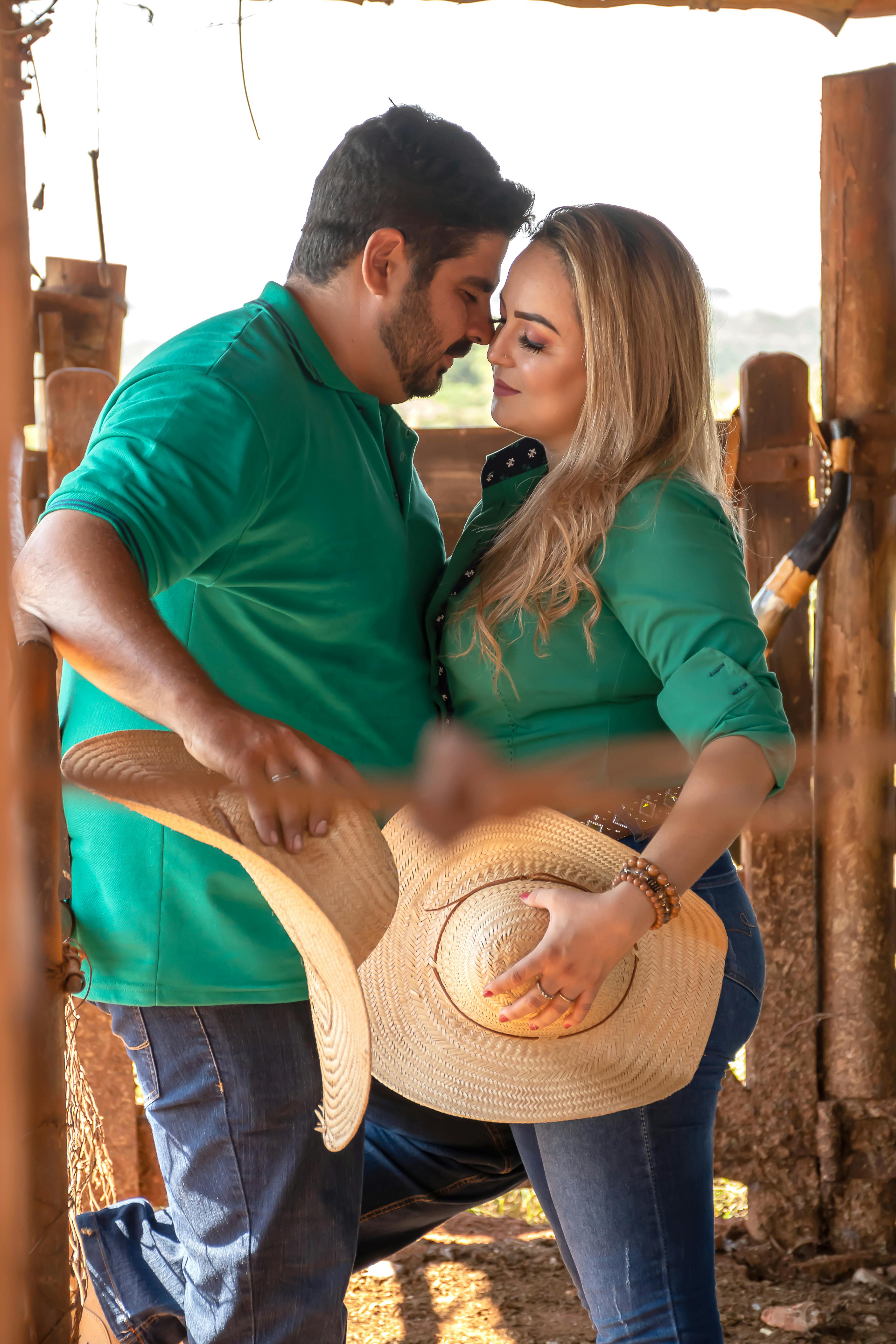 a couple in green shirts kissing holding woven hats