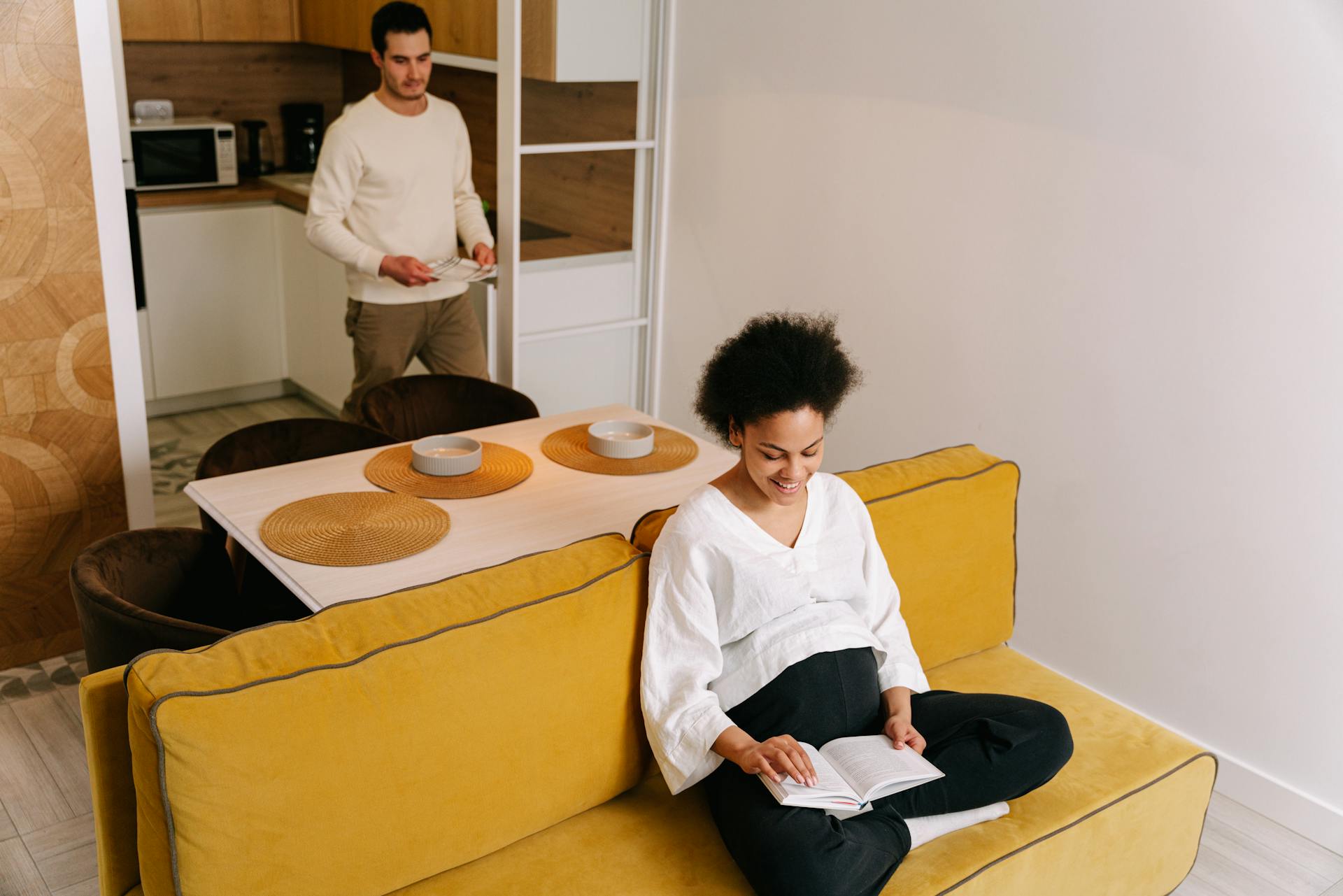 Pregnant Woman Sitting on Yellow Sofa and Reading a Book