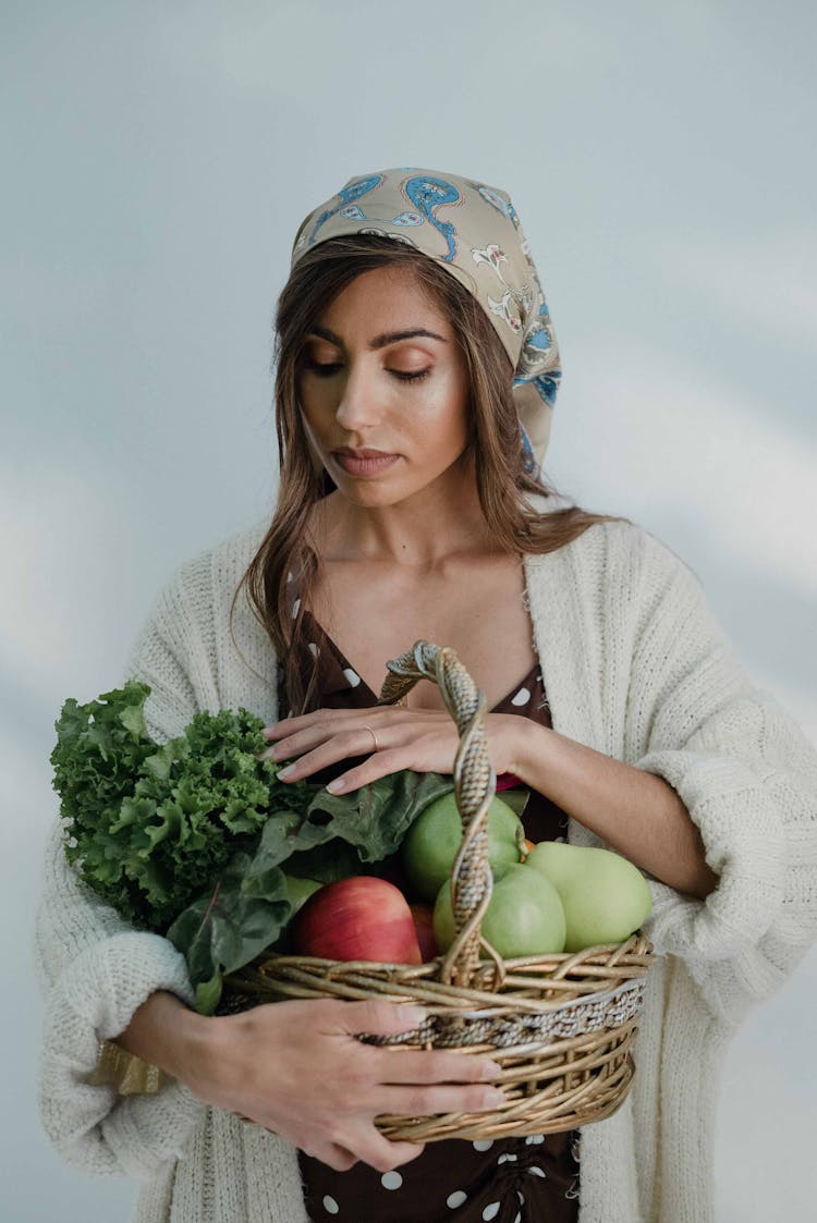 A Woman Holding A Basket Of Fresh Fruits And Vegetables