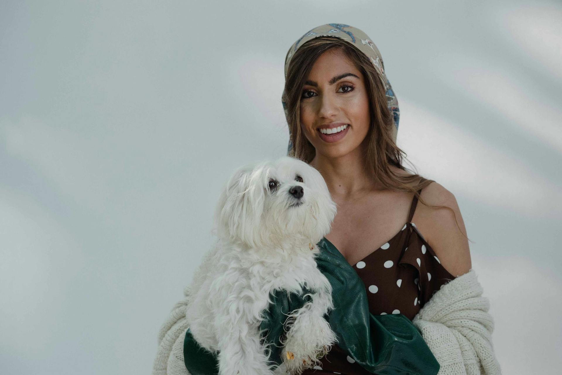 Een vrouw poseert met een Maltese hond