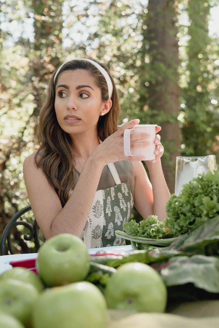 Woman Drinking Tea With Fruits And Vegetables On The Table 