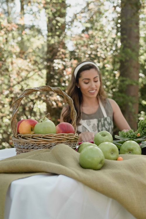 Free Woman in apron arranging apples in an outdoor setting, capturing a fresh and natural ambiance. Stock Photo