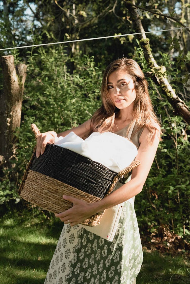 Portrait Of A Woman Carrying Basket With Laundry In A Garden