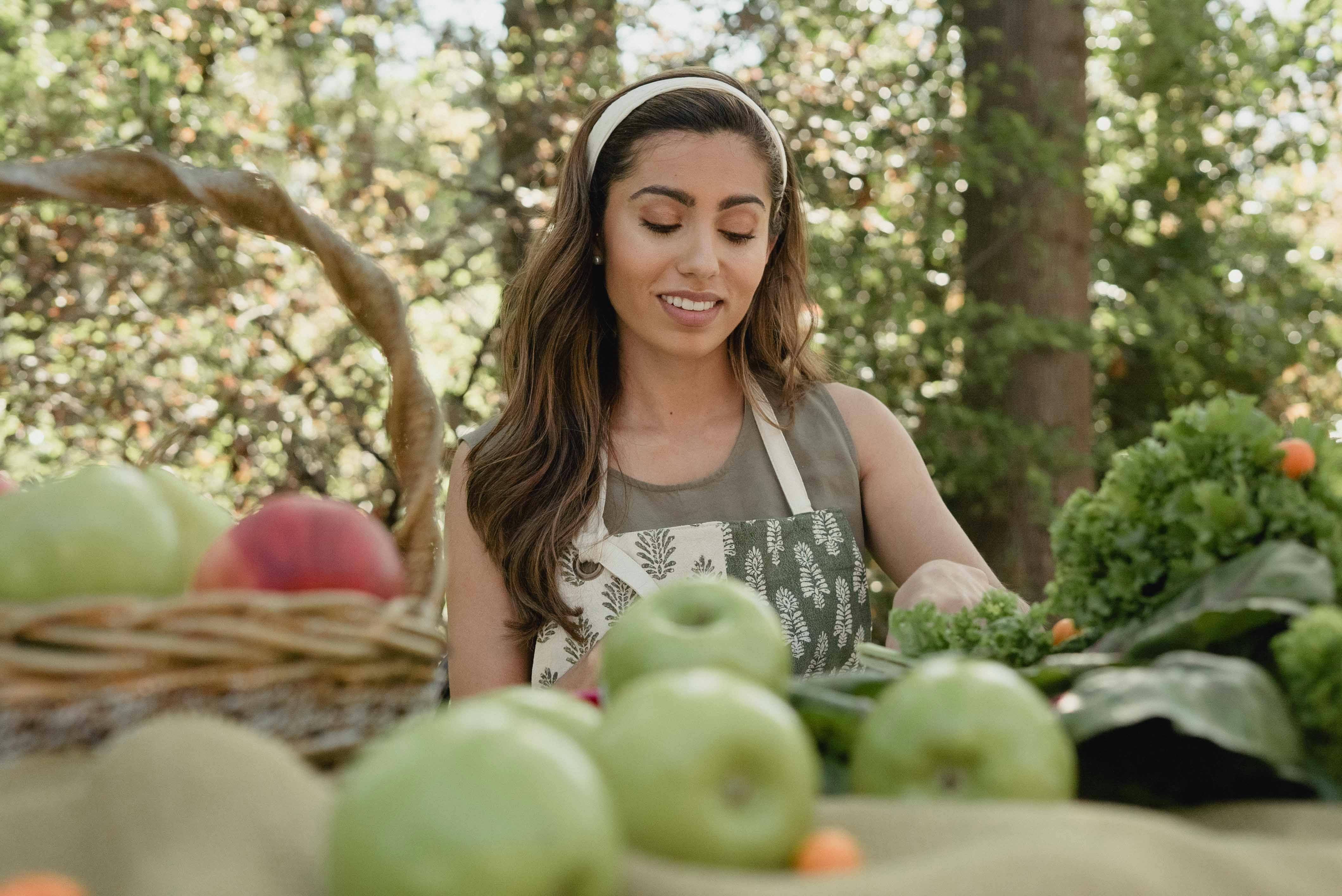 A Woman at a Table With Fresh Fruits and Vegetables