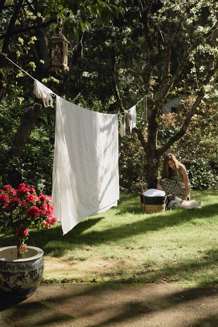 Woman Playing With The Dog In The Garden Next To Laundry Hanging On Ropes 